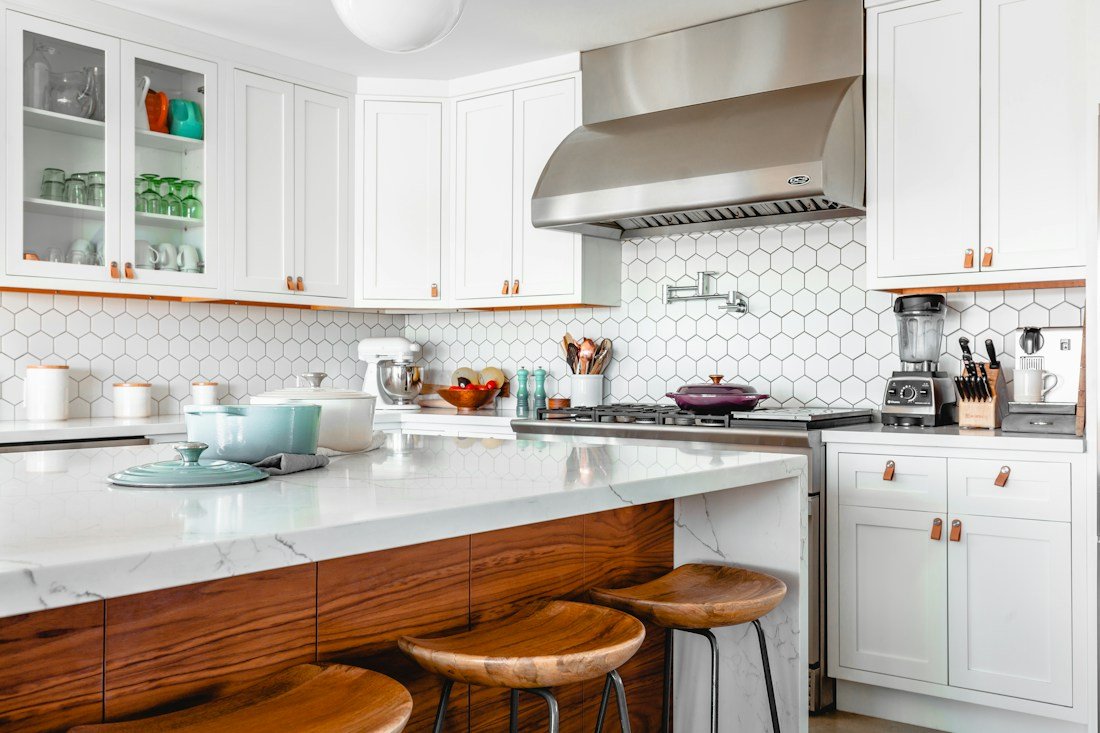 Fitted kitchen with household appliances and stainless steel extraction hood